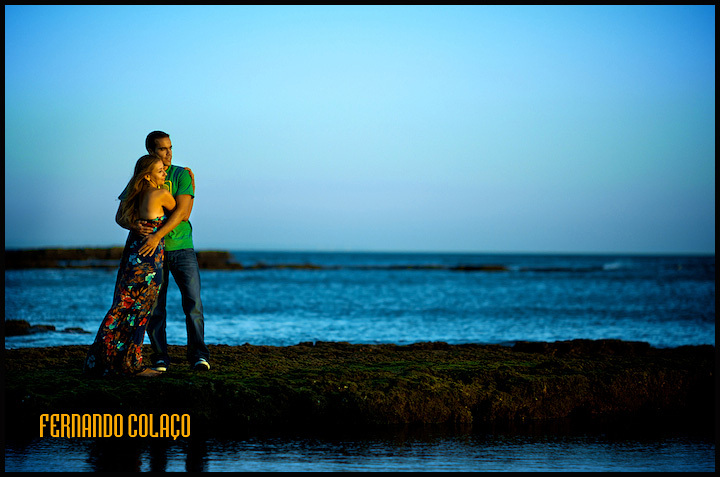 Em frente ao mar na praia das Avencas, o casal abraçado em sessão de namoro.