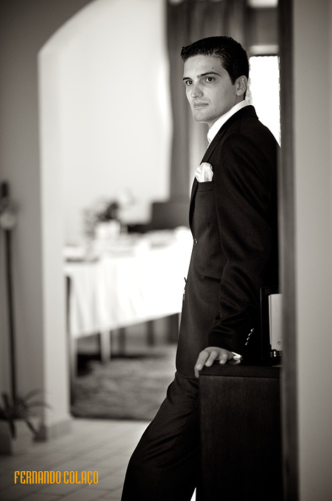 Portrait of the groom leaning on a piece of furniture.