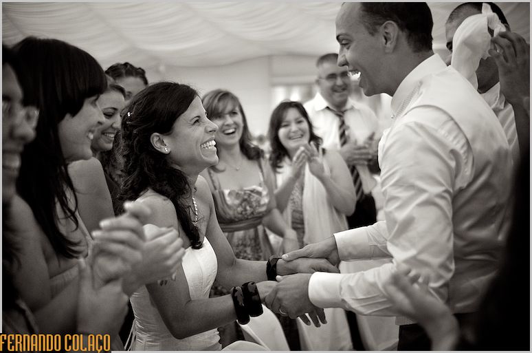 Os noivos riem muito um para o outro no meio de convidados, no fim de um jogo.