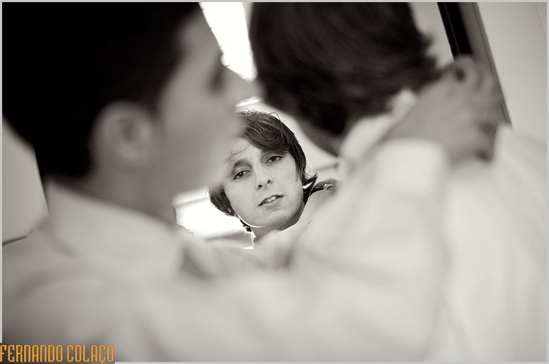 Groom's face, in a mirror, between him and a friend who helps him, blurred.