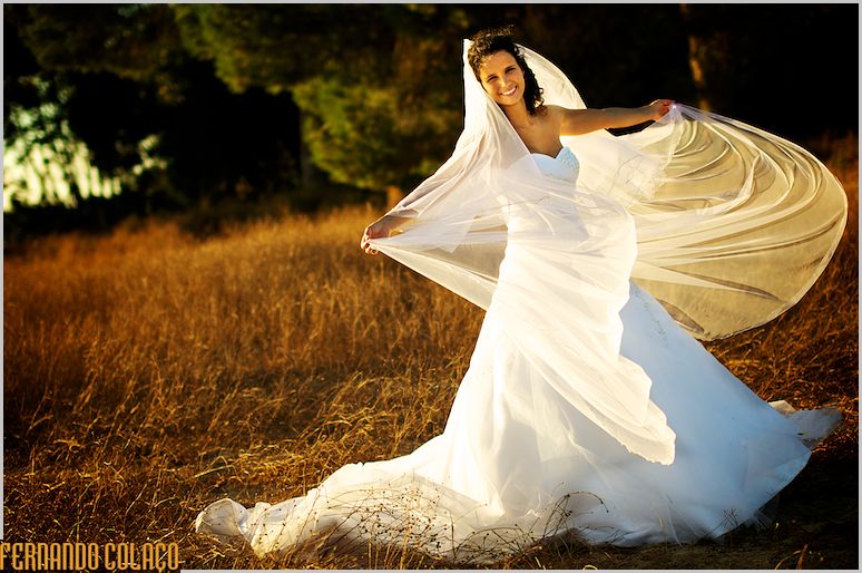 Bride with her veil blowing in the wind, in a golden late afternoon light.