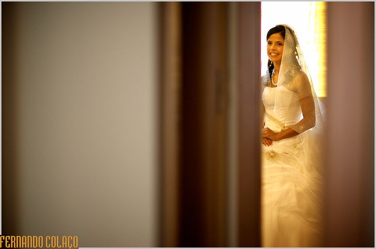 Seen through a doorway, the bride in golden light.