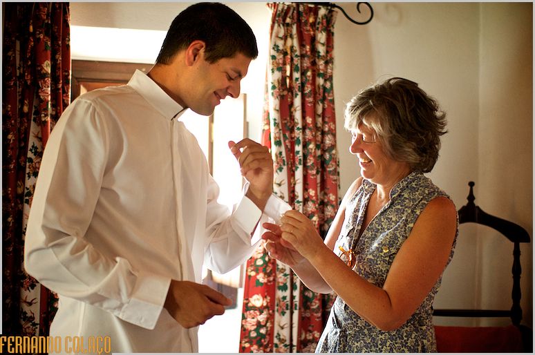 O noivo com a sua mãe que o ajuda com os botões de punho.
