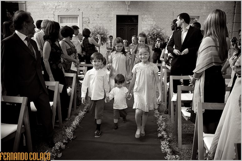Crianças percorrem a ala que leva ao altar da cerimónia do casamento, entre convidados.
