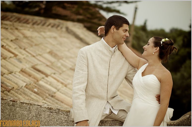 Perto do telhado de uma casa, o casal de recém casados olha um para o outro.