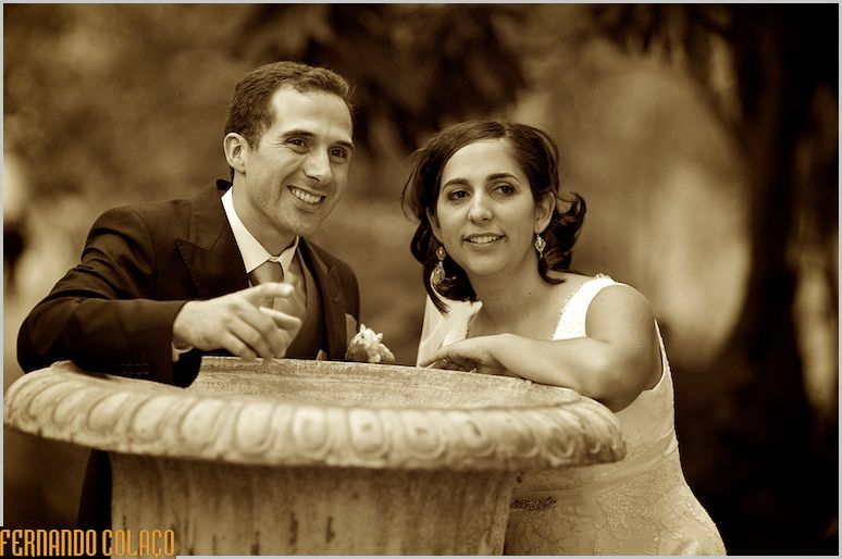 Debruçados sobre um grande vaso antigo do jardim da Quinta das Sentieras em Abrantes, os noivos em conversa, vistos pelo fotógrafo de casamentos.