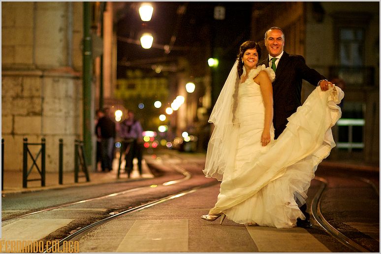 O noivo a segurar a cauda do vestido da noiva, numa passadeira da Rua do Arsenal em Lisboa.
