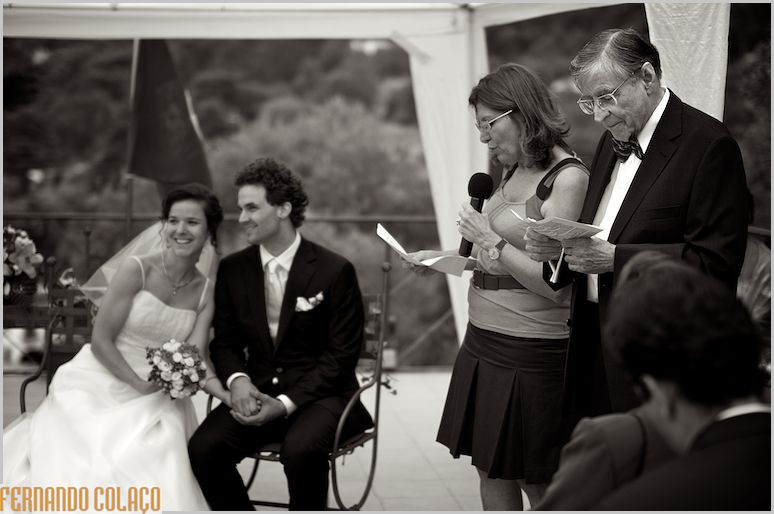 O tradutor e a tradutora da cerimónia do casamento, com os noivos ao fundo.