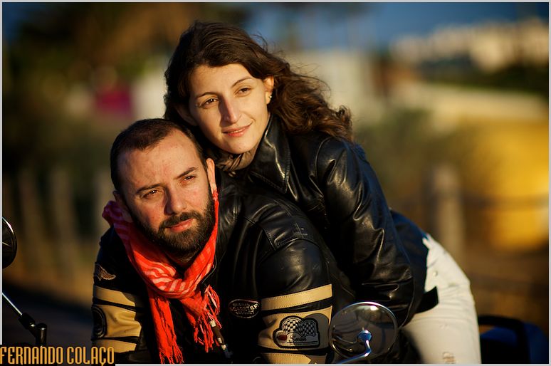 Sobre a sua moto, o casal assiste ao pôr do sol junto da paria da Bafureira na Parede.