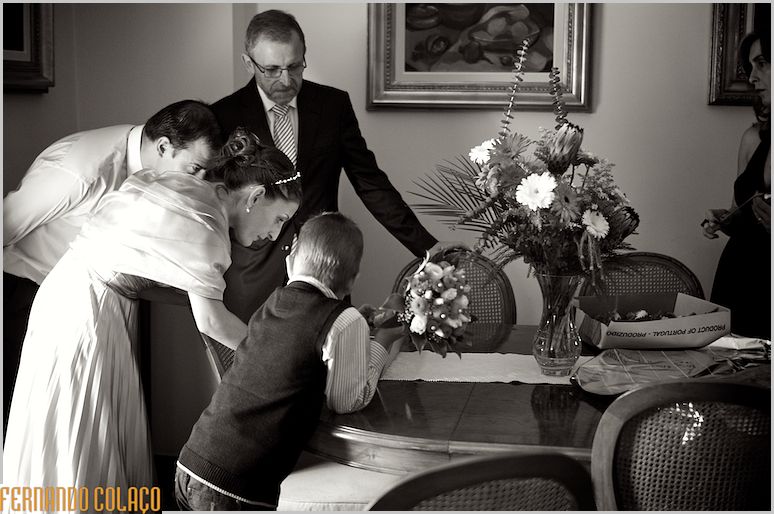 A noiva, numa mesa, verifica algo, junto da família.