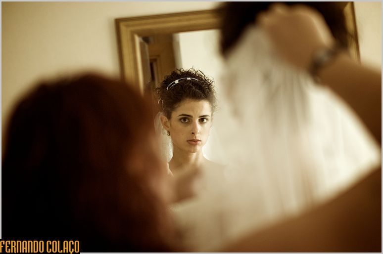 Bride, in a mirror, sees how the veil looks.