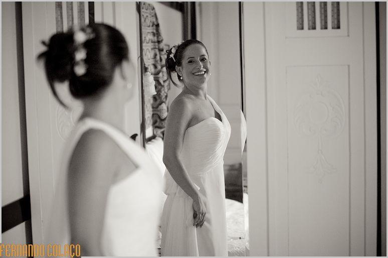 The bride sees herself in the mirror of a piece of furniture.