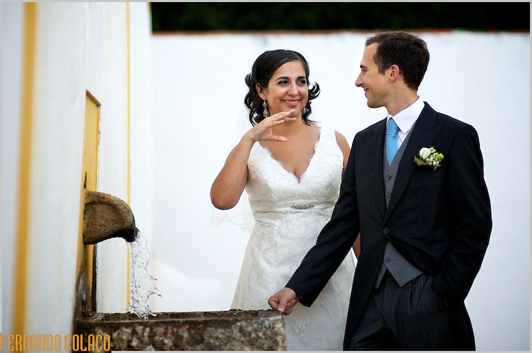 The bride and groom drink fresh water from a fountain at Quinta das Sentiras.