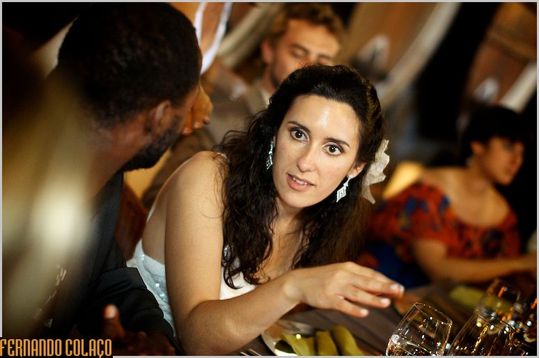 The bride, at the meal table, looks at the wedding photographer.