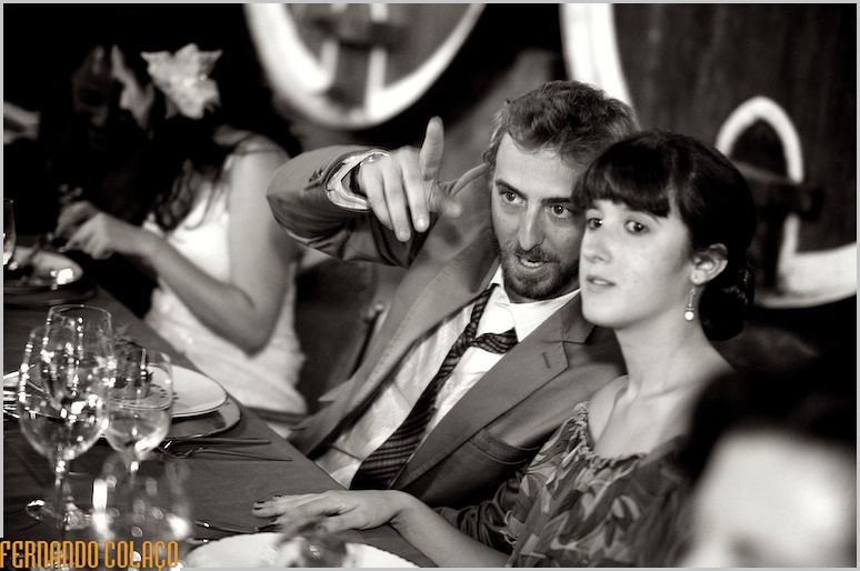 The bride in conversation with a guest points to something.