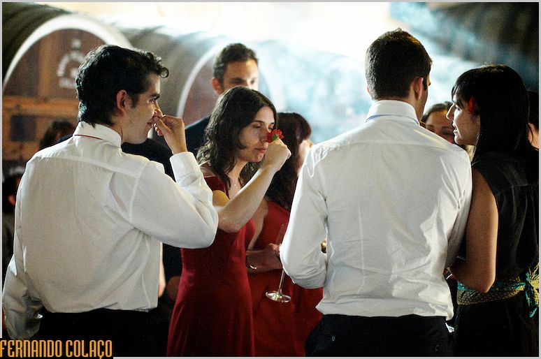 Wedding guests in conversation while a guest smells a flower.