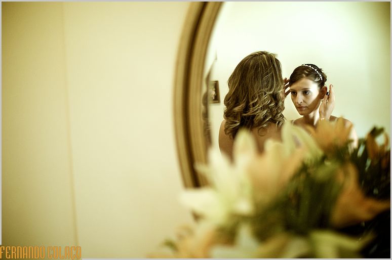 Mother of the bride puts the tiara in her hair, in a mirror.