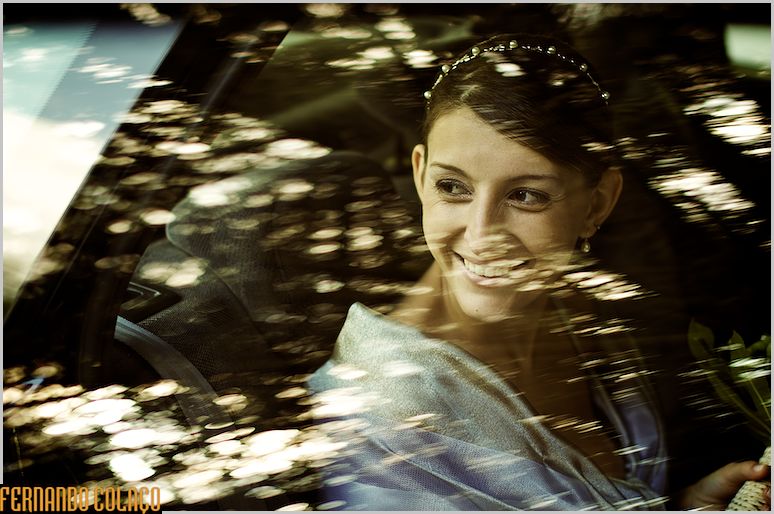 Bride in the car with reflections in the door glass, arriving at Quinta do Senhor da Serra in Belas, by the wedding photographer.