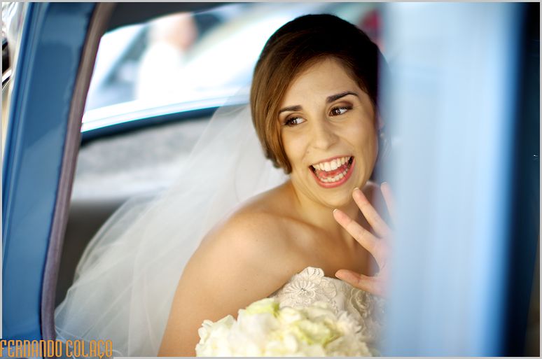 A noiva, dentro do automóvel, despede-se dos vizinhos, quando parte para a cerimónia do casamento.