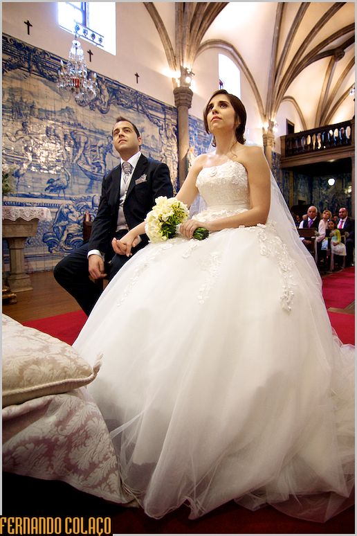 O casal sentado enquanto escuta o padre na homilia, durante o casamento.