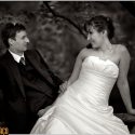 Sentados numa sebe, os noivos olhando um para o outro, na sessão com o fotógrafo de casamento na Quinta da Hera na Covilhã.