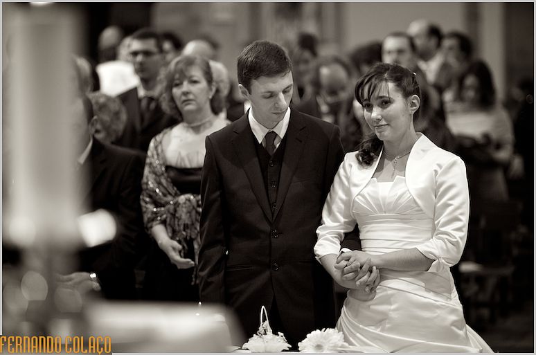 The bride and groom holding hands at the altar of the Mother Church of Fundão.