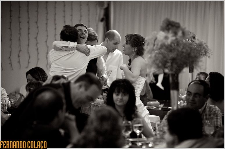 The groom is embraced by a guest with great effusion, along with the bride, as they distribute gifts.