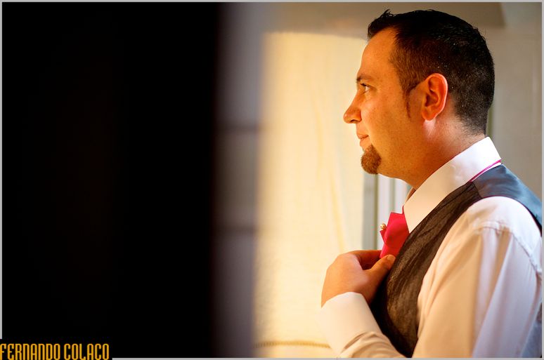 Groom, in profile, with his hand on his tie.