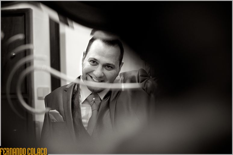 Through an embossed windowpane, the groom smiles.