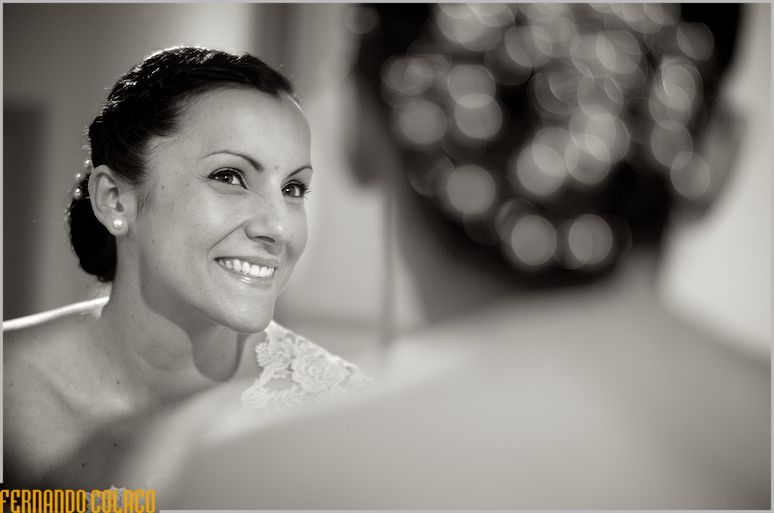 Looking at herself in a mirror, the bride smiles satisfied.