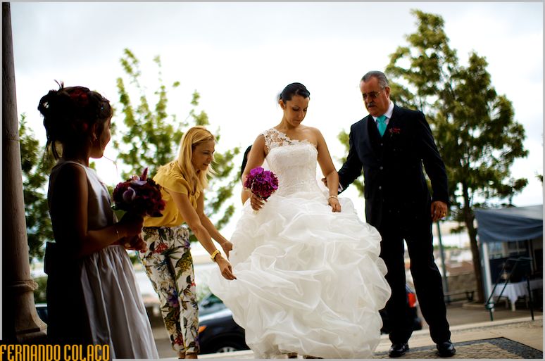 The bride, the father, a girl and a friend who adjusts her dress to enter the church.