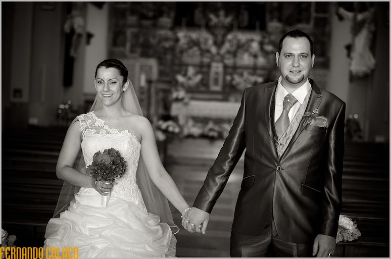 Hand in hand, the bride and groom cross the church to the exit.