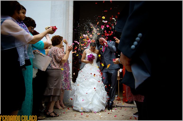 Wedding guests throw rice and flower petals at the bride and groom as they leave the church.