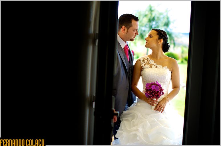The couple walking through a door, looking at each other.