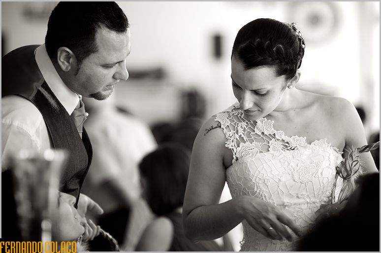 The newly married couple talk to a guest, when they offer her a gift.
