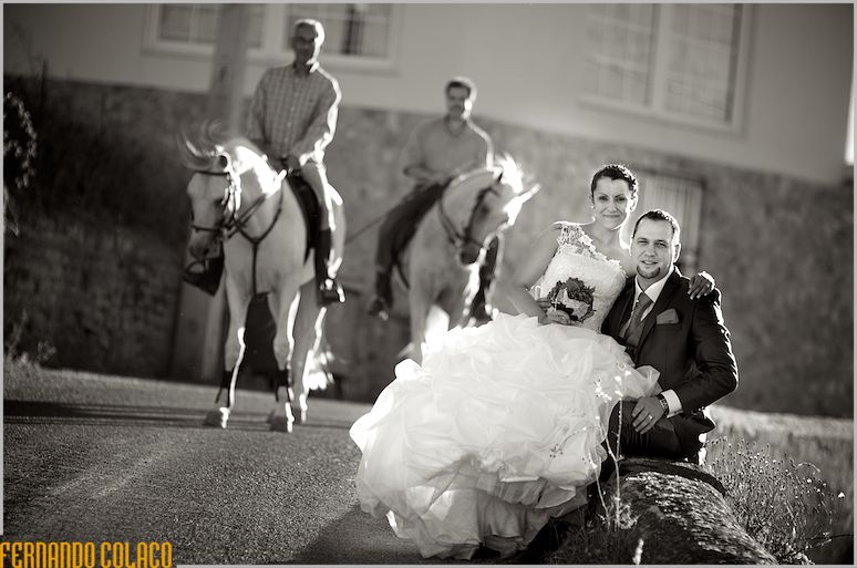 The newlywed couple sitting on a wall outside Quinta do Palhas, with two knights in the background.