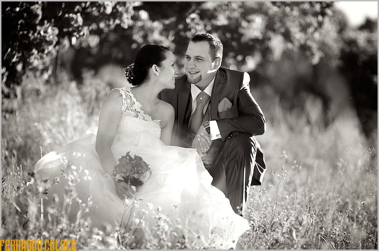 Sitting in the midst of wildflowers in an orchard, the bride and groom talk.