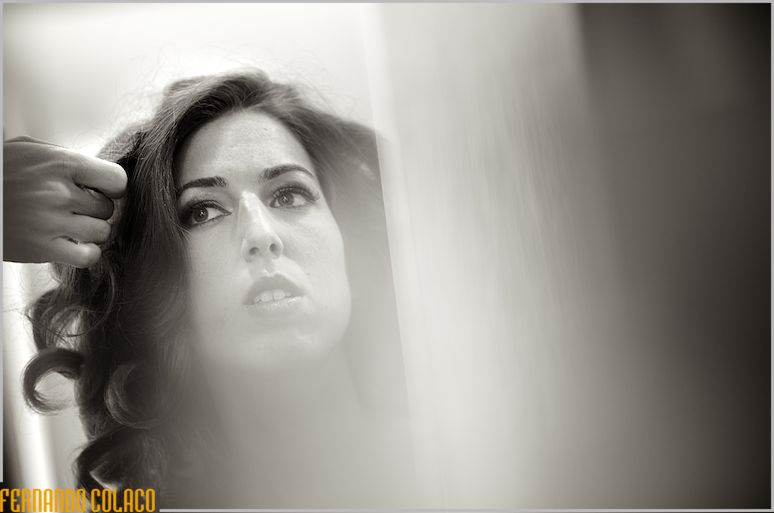 Behind a veil of light, the bride's face and a hand combing her hair.