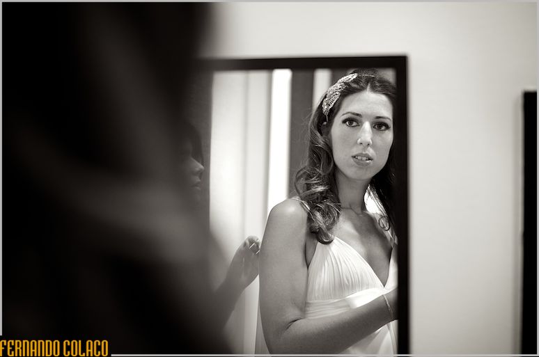 The bride checks her hairstyle in the mirror.