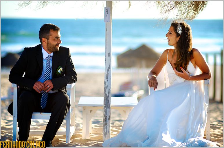 The couple sitting under a beach umbrella.