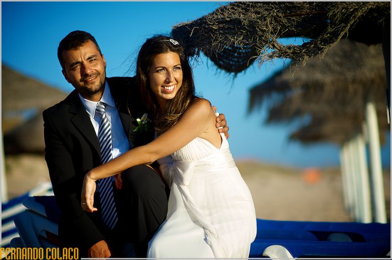 The bride and groom sitting on a chair at Praia da Sereia, in the photo session with the wedding photographer.