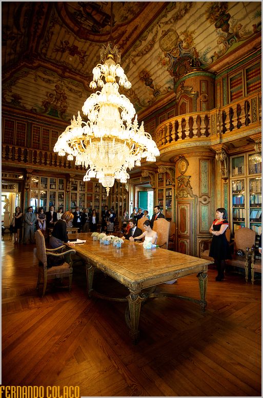 The wedding ceremony room, and its large chandelier, with the bride and groom and guests.