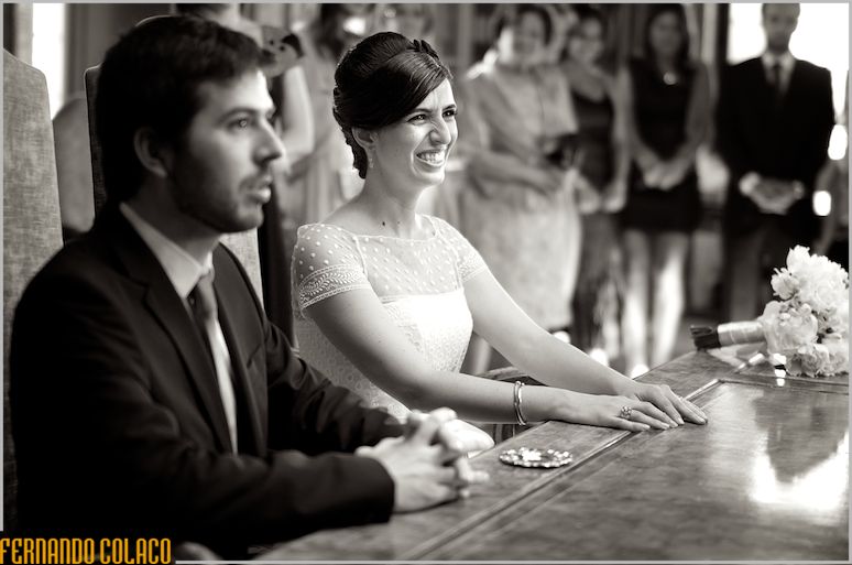 The bride laughs, during the wedding ceremony, between the groom and the guests.