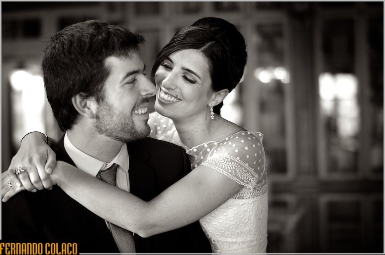 The bride hugs the groom by the neck and smiles at him.