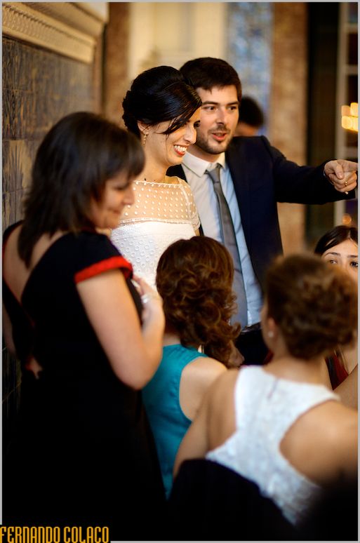 The groom, with the bride, in conversation with guests.