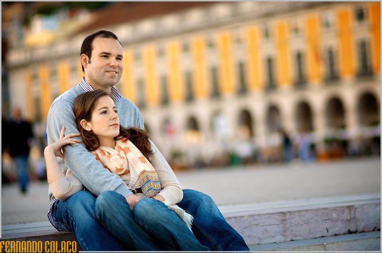 The couple, in the elopement session, sitting on a step in Praça do Comércio in Lisbon.