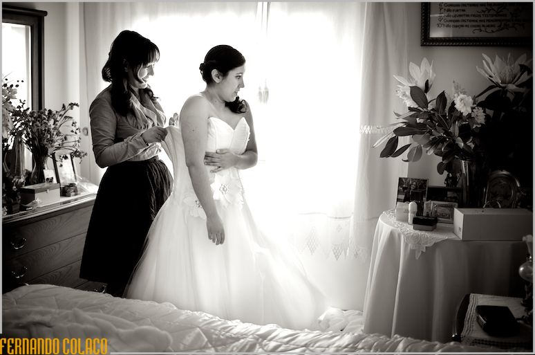 Bride helped by her sister in dressing her wedding dress.