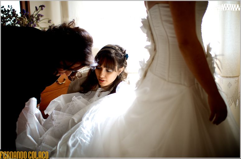 The bride's mother and sister adjusting the train of their wedding dress.