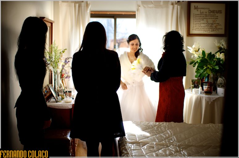 With two friends watching, the bride's mother gives her two yellow flowers.