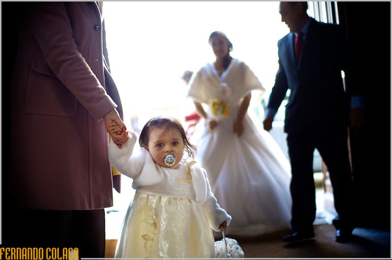 Small girl with the basket of rings and the bride in the background, blurred.
